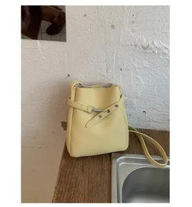 Sac seau en cuir synthétique jaune avec détail de sangle à anneau en métal élégant.