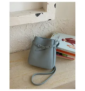 Détail de petit sac seau bleu clair présentant une texture en cuir PU délicat et boucle en métal.
