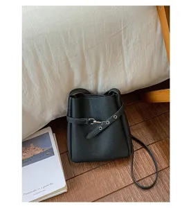 Gros plan de détail du sac seau en cuir noir sur sol en bois avec boucle élégante.