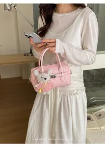Rosa strukturierte Bowlingtasche Detail mit Ledertextur und süßem Plüschhasen Anhänger.