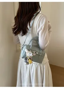 Hellblaue Umhängetasche aus Leder mit Häkelhase Anhänger und Metallverschluss für Damen.