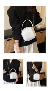 Detaillierte Ansicht der weißen Ledertasche mit besonderem Paneeldesign und Kette.
