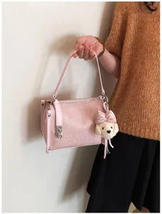 Nahaufnahme einer rosa Umhängetasche mit süßem Plüschbären-Anhänger und schickem Metallverschluss.