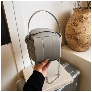 Graue Handtasche im Detail mit modernem geometrischem Design, Henkel und zilveren Kette.