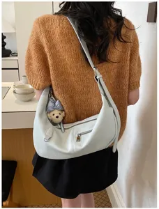 Lässige Hobo Umhängetasche Detail, stilvolles Halbmond-Design mit Bär-Anhänger und Reißverschluss.