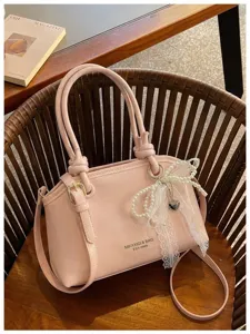 Rosa Handtasche Detail mit Perlen-Spitzen-Schleife Anhänger und doppelten Griffen.