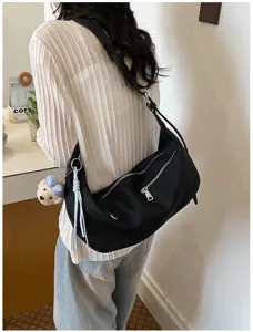 Minimalistische schwarze Schultertasche mit Reißverschlusstasche und Bärenanhänger für Damen.