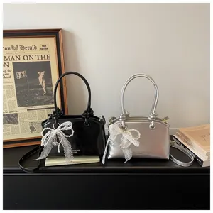 Schicke Damenhandtasche in Schwarz und Silber mit eleganten Spitzen-Perlen-Schleifenanhängern.