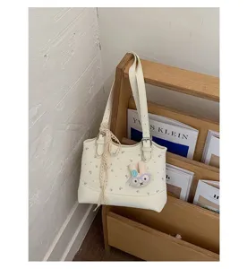 Chic white floral shoulder bag detail, stylish underarm bag with cute rabbit pendant.
