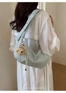 Detailansicht der hellblauen Leder Schultertasche mit süßem Plüschbären Anhänger.