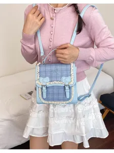 Detail view of a light blue plaid mini backpack with sweet lace trim, bows and cute buckles.