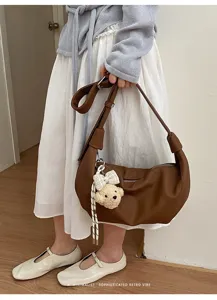 Detailansicht der modischen braunen Leder-Hobo-Tasche mit einem süßen flauschigen Bärenanhänger.