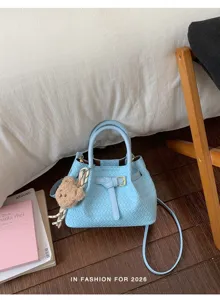 Hellblaue geflochtene Beuteltasche mit modischer Schnalle und Bär-Anhänger für Damen.