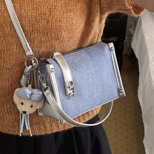 Stylische blaue Damen Umhängetasche aus Jeansoptik mit Bär Anhänger für modebewusste Frauen.