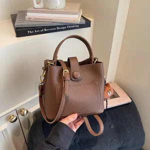 Détail de sac seau en cuir marron avec texture premium, poignée et bandoulière réglable.