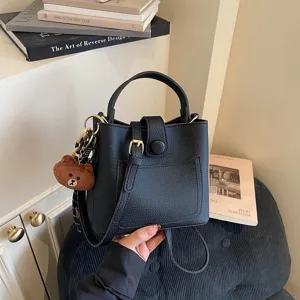Gros plan détail du sac seau élégant en cuir noir avec joli pendentif en peluche d'ours.