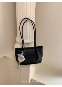 Detalle de bolso de hombro negro minimalista, bolso shopper elegante con bonito colgante.