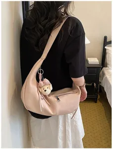 Detailaufnahme einer minimalistischen Halbmond-Umhängetasche aus rosa PU-Leder mit Anhänger.
