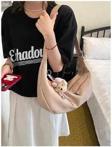 Nahaufnahme der rosa Leder Hobo Schultertasche mit süßem Bärenanhänger und Reißverschluss.