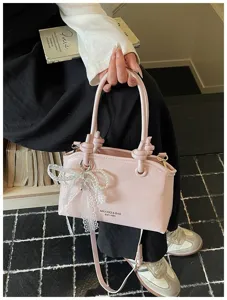 Rosa Lackleder Handtasche Detail mit Perlen-Spitzen-Schleife und doppelten Tragegriffen.