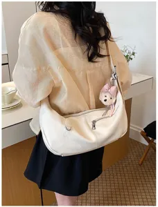 Detailansicht der stilvollen weißen slouchy Schultertasche mit einem süßen Bärenanhänger.