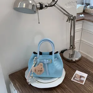 Light blue woven leather handbag stylish bucket bag with top handle and cute bear pendant.