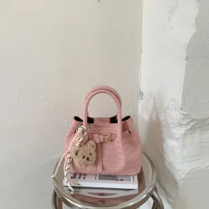 Pink woven bucket handbag for women, chic spring shoulder bag with cute bear charm.