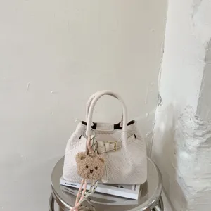 Chic white woven handbag for women, elegant leather tote bag with cute bear charm and handle.