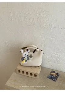 Minimalistische cremeweiße Litschistruktur Beuteltasche mit süßem Strick-Kaninchenanhänger.