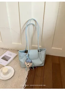 Vista detallada de elegante bolso de hombro de cuero azul claro con dije de felpa lindo.
