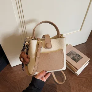 Vue détaillée du sac seau élégant en cuir bicolore avec poignée supérieure et sangle.