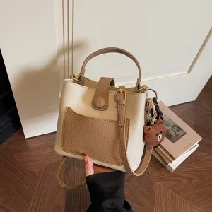 Chic sac seau bicolore, élégant sac à main porté épaule et bandoulière avec pendentif.