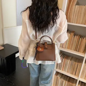 Vue détaillée du sac seau en cuir marron, style bandoulière chic avec charmant pendentif.
