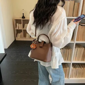 Sac seau élégant en cuir marron, sac bandoulière polyvalent avec joli pendentif d'ours.
