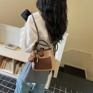 Vue détaillée du sac seau bandoulière tendance pour femme avec pendentif et chaîne.
