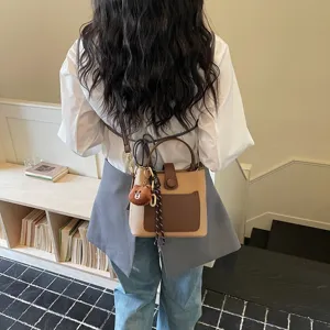 Vue détaillée d'un sac seau bicolore tendance avec un joli pendentif en peluche d'ours.