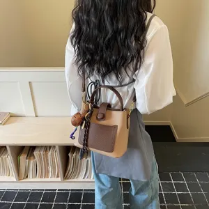 Vue détaillée d'un sac seau bicolore élégant avec un charmant pendentif ours mignon.