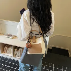 Chic sac à main seau bicolore avec charm en peluche d'ours mignon, sac bandoulière élégant.