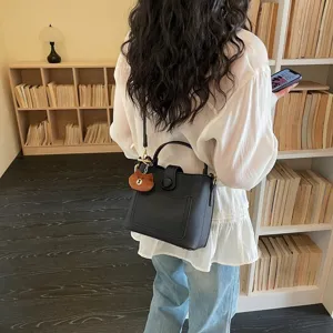 Sac seau noir élégant avec charm d'ours, sac à bandoulière chic pour un usage quotidien.