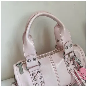 Rosa Lederhandtasche Detail zeigt geflochtenen Griff, Metallnieten und Reißverschluss.