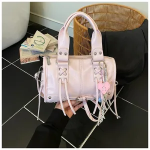 Rosa Leder Motorrad Handtasche mit stylischen Nieten, Quasten und Herz Anhänger Detail.