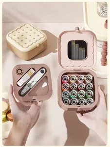 Boite de kit de couture portable en forme de biscuit avec fils colores, ciseaux et ruban.