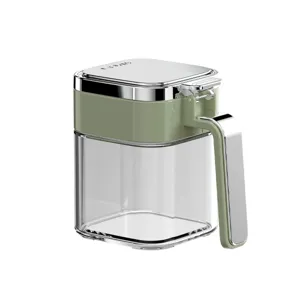 Clear glass seasoning jar with green lid and handle, ideal for kitchen storage use.