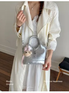 Sac seau métallique argenté pour femme, cabas bandoulière élégant avec pendentif ours.