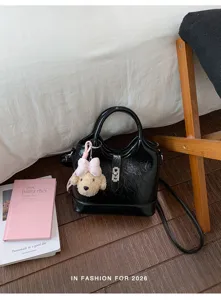 Détail de sac seau en cuir vernis noir avec joli pendentif chien et serrure métal, chic.