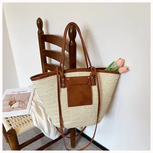 Gros plan détail du sac cabas en paille tissée avec poignées en cuir PU marron et poche avant.