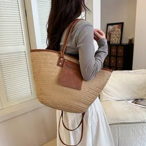 Grand cabas en paille avec garniture en cuir synthétique marron et bretelles pour femmes.