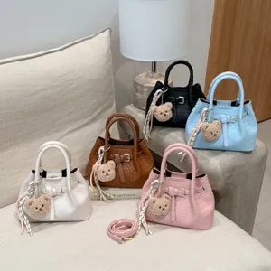 Stylish woven bucket bag for women, trendy leather handbag with cute bear pendant and strap.