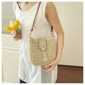 Vista detallada del elegante bolso de hombro de paja de moda con solapa de cuentas y borla.