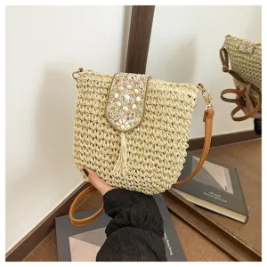 Detalle de elegante bolso cruzado de paja tejida, con solapa de cuentas, conchas y borla.